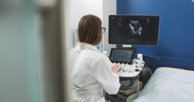 Ultrason tarama makinesi operatörü oturuyor ve ekrana bakıyor, işe hazırlanıyor. Modern ultrason cihazları üzerinde çalışan beyaz kadın doktorun arka planı..