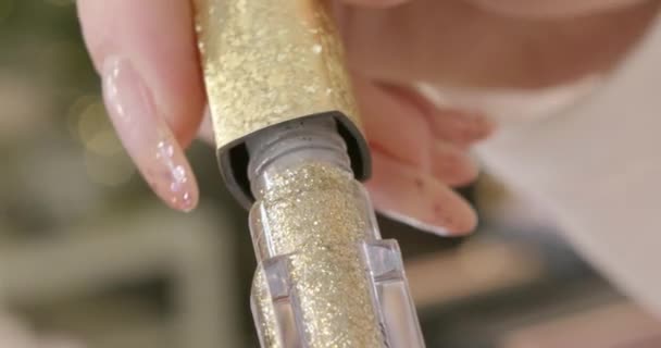 Smalto glitter oro in bottiglia con pennello. Close Up vista dall'alto della bottiglia aperta di moderno smalto alla moda di colore oro con scintille lucide nella consistenza. — Video Stock
