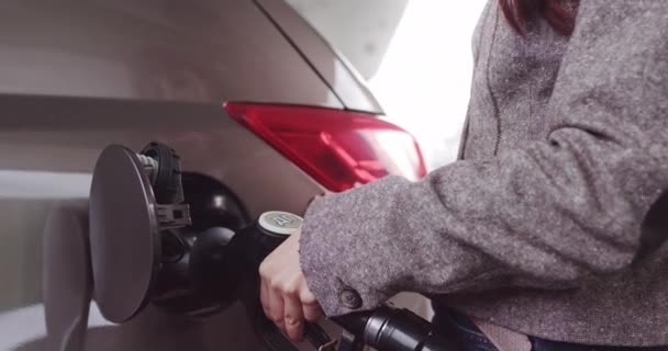Увидел молодую женщину, стоящую рядом с машиной и заправляющую ее на заправке. Женщины заправляют машину на закате. Заполнение бензина бензиновым топливом в автомобиле на заправке. Концепция топлива — стоковое видео