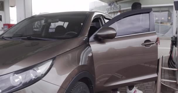 Portrait de jeune Afro-Américain à la station-service extérieure ravitailler sa voiture de luxe avec de l'essence, l'insertion de buse dans le bouchon de carburant d'une voiture — Video