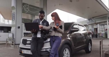 Benzin istasyonunda çalış ve mola ver. Genç Afrikalı bir adam ve beyaz bir bayanın dijital tabletle birbirlerini gösterirken çekilmiş bir fotoğrafı. Çeviri: HAYATININ ENERJİSİ