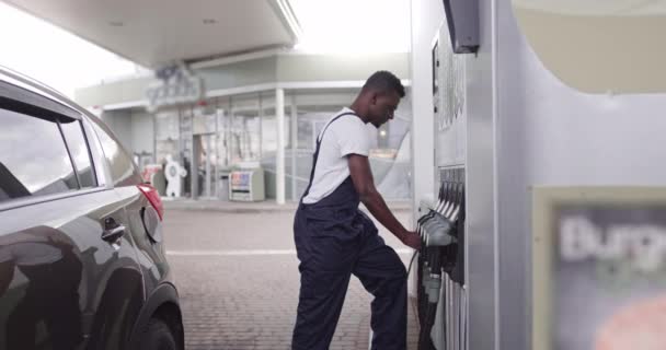 Benzin istasyonunda çalışan yakışıklı Afrikalı genç bir erkek müşterinin arabasına benzin dolduruyor. — Stok video