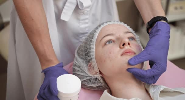 整形外科医生检查漂亮的女人的脸，用戴手套的手触摸它，在整形外科手术前检查她的脸。一位皮肤有问题的少女面部特写 — 图库视频影像