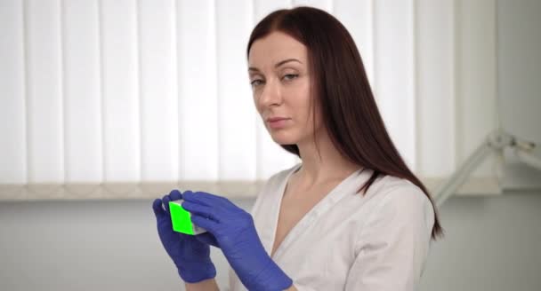 Közelkép a magabiztos orvosi nő keres kamera, Beszéd tabletták Box Info. Orvos a kamerának, mutat egy doboz gyógyszert. Az orvos bemutatja az új gyógyszert a zöld képernyőn, Chroma Key. — Stock videók
