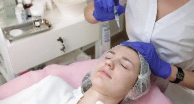 Yaşlanma ve kırışıklık önleyici terapi. Cilt bakımı ve güzellik. Kadın doktor güzellik uzmanına yakın çekim, modern kozmetoloji merkezinde kadınların yüzüne kozmetik serumu uyguluyor..