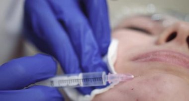 Maske ve eldiven giyen doktor kozmetik uzmanı, yüz bölgesinin tedavisi için mezoterapi enjeksiyonu yapıyor, gençleştirme. Deri hidrasyonu ve gençleştirme,