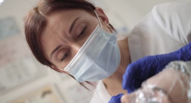 Портрет молодої медсестри-медика-хірурга, що стоїть у лікарняній палаті під час операції. Близьке обличчя жінки-лікаря в захисній масці, лікарська маска. — стокове відео
