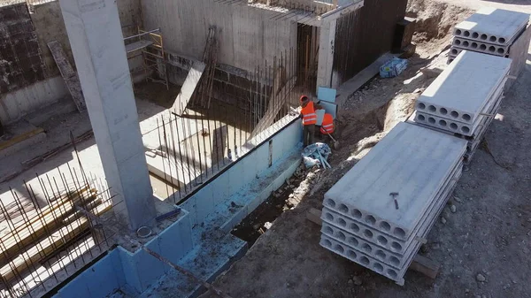 Bauindustrie, Monolithische Rahmentechnologie. Top-Ansicht von Mitarbeitern, die mit Bauarbeiten beschäftigt sind. Bauarbeiter isolieren das Fundament mit Schaum. Arbeiten mit Stahlbetonkonstruktionen — Stockfoto