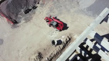 Güçlendirilmiş beton yapı ve tekerlek yükleyicisinin üst görüntüsü. İnşaat sahasında Öndeki Yükleyici, iş için başlığı değiştirmeye hazırlanıyor. Buldozer inşaat alanında çalışıyor, havadan veya üstten..