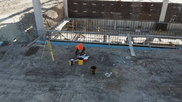 En ugjenkjennelig anleggsleder ser på plantegningene mens han står utenfor et moderne hus. Mannlig byggeleder, arkitekt i hard hatt, med tegningstegning – stockfoto