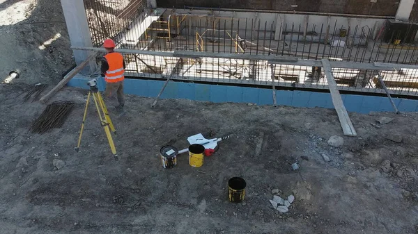 En ugjenkjennelig anleggsleder ser på plantegningene mens han står utenfor et moderne hus. Mannlig byggeleder, arkitekt i hard hatt, med tegningstegning – stockfoto