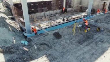 İnşaat alanı yöneticisi kat planlarına bakıyor. Yüksekten bakıldığında, bir inşaat alanında çalışan çeşitli profesyonellerden oluşan bir grup. İnşaat alanında birçok farklı işçi var.