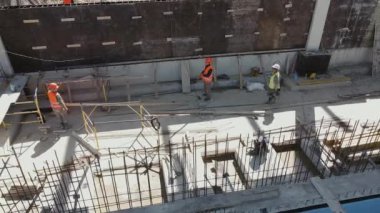 İşçilerle dolu büyük bir inşaat alanı. Modern monolitik yapı. İnşaat alanında birçok farklı işçi var. Güçlendirilmiş beton yapıların inşası