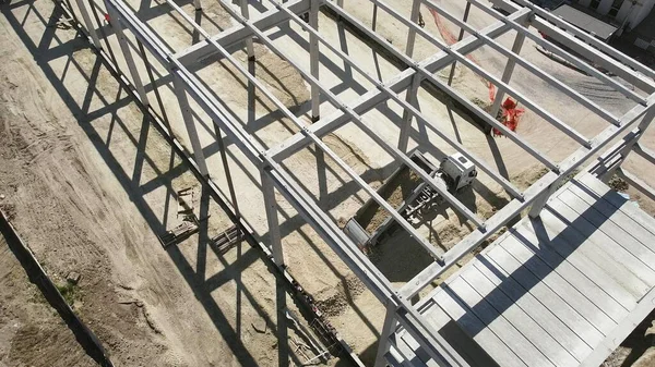 Cadre en béton armé d'un bâtiment industriel. Vol de caméra sur un chantier de construction. Poutres avec renfort en acier. Camion à benne basculante décharge sable dans la construction. Vue aérienne. Déchargement du sol — Photo