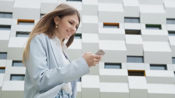 Business woman using smartphone texting female executive checking emails. Business. Social Network. Apps. Career people. Shooting on the street near the office. The girl looks at the camera and smiles — Stock Video