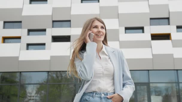 Кавказька Впевнена Молода Бізнес Жінка в Білому Шерті розмовляє по телефону за межами сучасного офісу будівлі. Середній Long Low Angle 4K Корпоративний постріл з повільним рухом. Кар'єра — стокове відео