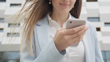 Sosyal medya uygulamasını akıllı telefon mesajlarında kullanan zarif genç bir bayana açık havada gülümseyen haberler geliyor. İnsan portreleri. Teknoloji. Kapalı kapılar ardında neşeli bir kız telefonda iyi haberler okuyor..