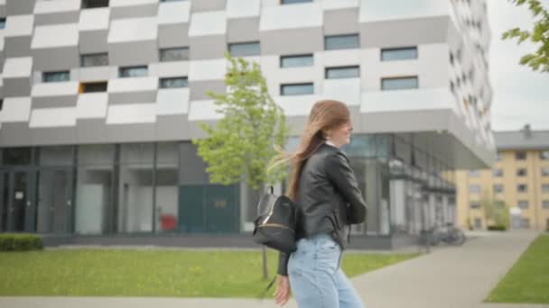 Mujer elegantemente vestida divirtiéndose al aire libre en traje de Jeans. Te ves feliz y agradable. Saltar y correr en la ciudad. Te ves preciosa. Retrato de estudiante sobre el fondo de un edificio — Vídeos de Stock