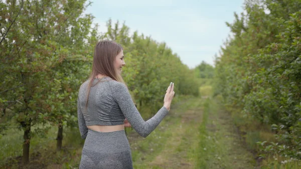 Giovane ragazza attraente sport riprese su un albero del telefono fotografato sullo sfondo della natura. Ragazza blogger indica la natura della fotocamera, il concetto di storie sulla protezione dell'ambiente degli alberi — Foto Stock