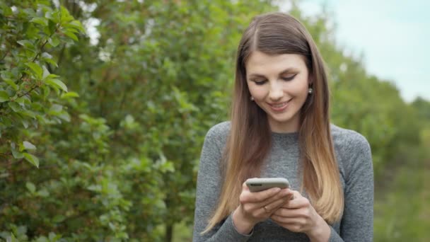 해피젊은 여성, 공원 야외에서 백지로 된 스마트폰을 사용하는 행복 한 여성 건강 도우미 나무 운동 여름 자연 과학 기술 여성달리기 선수 휴대 전화 작동 — 비디오