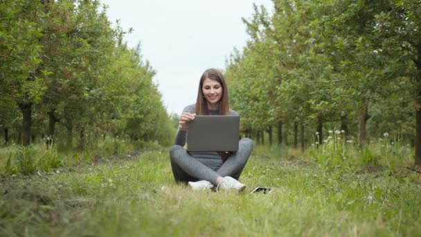 Mädchen sitzen im Park oder Wald und öffnen Laptop über die Natur. IT-Spezialist arbeitet an der Selbstisolation im Freien. Frauen, die geschäftlich oder freiberuflich in der Natur oder an der frischen Luft bei herrlichem Sonnenlicht arbeiten. — Stockvideo