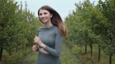 Yaz parkında genç bayan koşucu eğitimi. Spor salonundaki kadın dışarıda koşuyor. Sağlıklı koşu ve açık hava egzersizlerini, oyuncak bebek vuruşlarını hesaba katın. Spor Giyim 'deki Genç Formalı Kadın. Yavaş Hareket