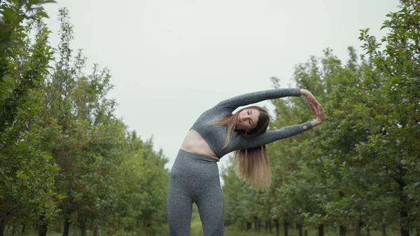 New normal sport outdoor, young fit sport woman stretching her body warm up before workout outdoor. The girl in sportswear exercises outside in the evening sunset for health and wellbeing.