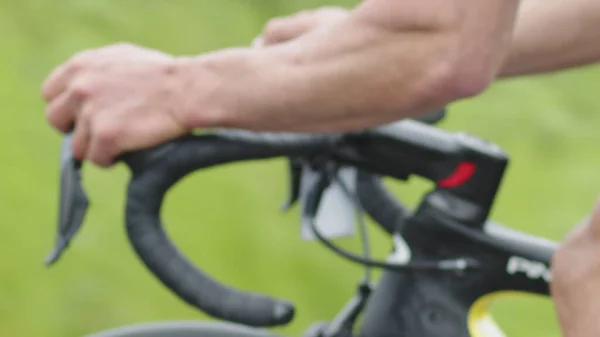 Closeup of the curved steering wheel of a road bike, the hands of a cyclist switching speed while driving on the road.
