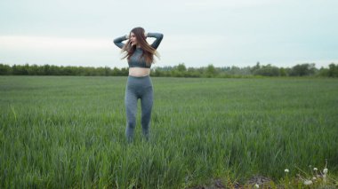 Kadın esneme ve ısınma koşusundan önce. Spor Giyim ve Isınma Antrenmanı. Açık havada spor yapan bir kadın. Koşu yaptıktan sonra kollarını esneten ve esneten bir kız..