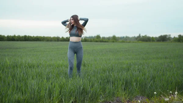 Kadın esneme ve ısınma koşusundan önce. Spor Giyim ve Isınma Antrenmanı. Açık havada spor yapan bir kadın. Koşu yaptıktan sonra kollarını esneten ve esneten bir kız..