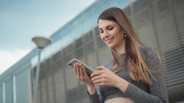 Fitness, sport and technology concept - happy smiling woman running outdoors. Close-up Of A Young Beautiful Sports Fitness Girl Holding A Smartphone In The Hands. Phone conversation during training