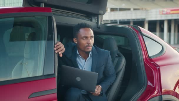 Muž s laptopem uvnitř nabíjející elektrické auto. Elektrické auto s nabíjecím kabelem v zástrčce. — Stock video