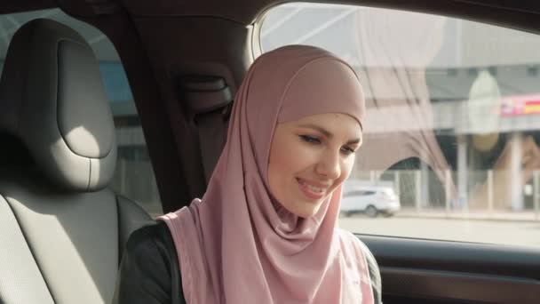 Красива жінка в традиційному одязі від об'єднаних арабських еміратів. Молода леді керує своєю машиною. Молода красива мусульманська дівчина в Хіджабі сидить в машині, спостерігаючи за камерою, концепція транспорту — стокове відео