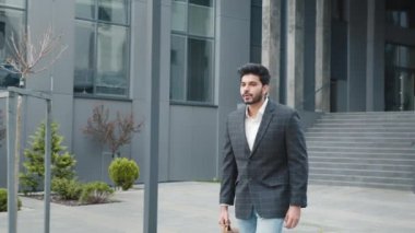 Şehir merkezindeki elit ofisin yakınındaki bir sokakta işadamının etrafında dolanırken çekilmiş. Şık giyimli yakışıklı müslüman işadamı açık havada elinde kahverengi deri bavulla dolaşıyor.