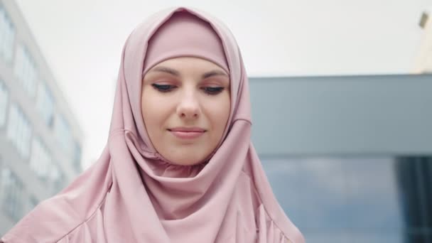穆斯林女商人站在办公中心附近.站在写字楼附近，手里拿着智能手机的美丽的穆斯林女子的低视角。穿着正装、头戴头巾的女商人 — 图库视频影像