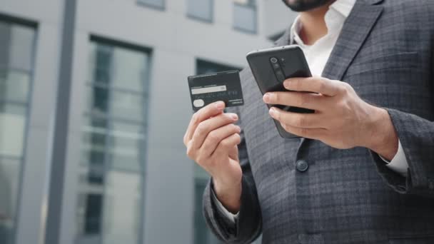 Detailní záběr mužských rukou držících moderní smartphone a kreditní kartu. Muslimský podnikatel stojící na ulici a užívající si online nakupování. Pojem gadgets, lidé a nákup. Hinduistický podnikatel — Stock video