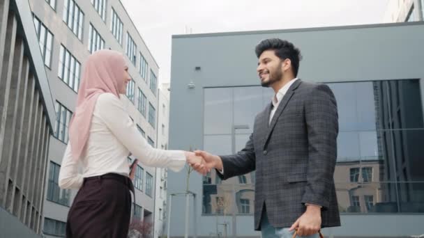 Szczęśliwy arabski mężczyzna i kobieta uścisk dłoni po udanej współpracy, stojąc w pobliżu nowoczesnego budynku biurowego. Pojęcie ludzi i pracy zespołowej. Mężczyzna i kobieta ściskający dłonie dla udanej transakcji — Wideo stockowe