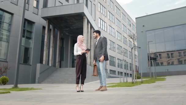 Mulher atraente em hijab segurando tablet digital em pé perto de seu colega muçulmano que usando smartphone moderno para tirar selfie. Conceito de negócio, pessoas e gadgets. Colegas de negócios sorridentes — Vídeo de Stock