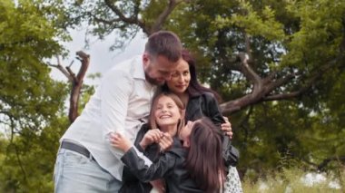 Mutlu genç ebeveynler yeşil bahçede şirin küçük kızlarıyla oynuyorlar. Kafkas ailesi hafta sonlarını temiz havada eğlenerek geçiriyor. İlişki ve ebeveynlik kavramı. Mutlu ebeveynler kızlarını oynuyor