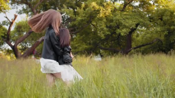 Duas meninas caucasianas em vestido de verão e jaqueta preta brincando juntas no jardim de verão. Irmãs bonitas em bom humor relaxando no ar fresco. Irmãs caucasianas brincando juntas no jardim verde — Vídeo de Stock