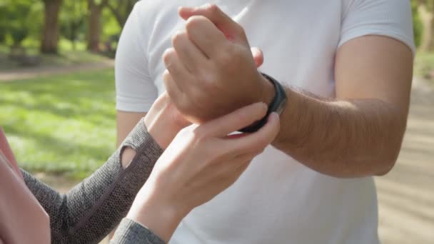 Jonge moslim vrouw in hijab zet op fitness horloge van Indiase knappe vriend. Kijk uit voor training. Fitness Watch als een geschenk aan een moslimvriend. vrouw met behulp van slimme horloge terwijl moslim guy ontspannen — Stockvideo