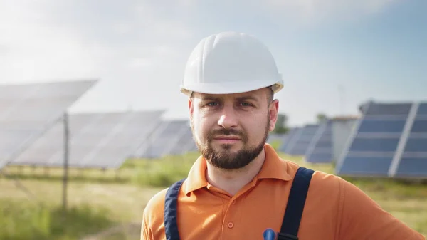 Portret męskiego inżyniera w twardym hełmie obracającego głową i patrzącego w kamerę. Pozytywny pracownik. Przemysł ekologiczny. Koncepcja farmy słonecznej. Koncepcja energii odnawialnej, technologii, przyszłości. — Zdjęcie stockowe