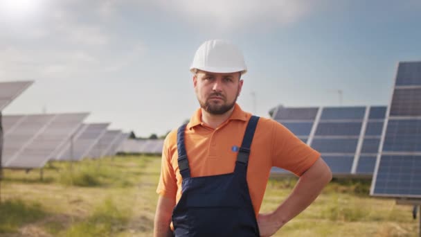 Trabajador de ecología de retratos en el campo de paneles solares. Gente industrial. Retrato de ingeniero masculino en casco duro girando cabeza y mirando a la cámara. Concepto de desarrollo de estaciones solares — Vídeos de Stock