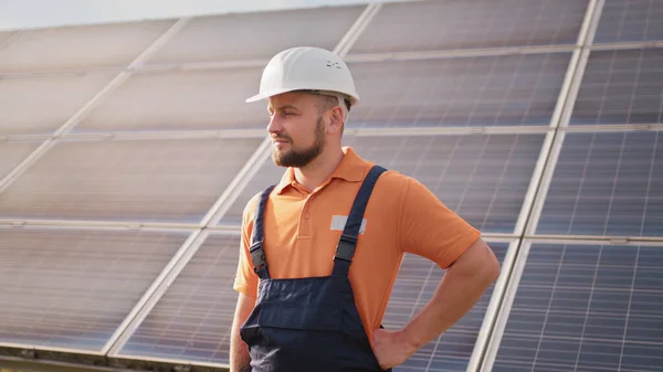 Muotokuva itsevarma insinööri aurinkokennojen maatilan teollisuudelle. Henkilökunta luottavainen aiheuttaa aurinkokenno paneeli asennus. Lähikuva muotokuva mies työntekijä suojakypärä seisoo lähellä aurinkopaneeli — kuvapankkivalokuva