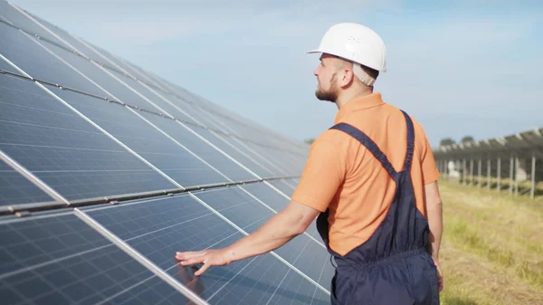 Sustainable green energy jobs, solar panel technician working with solar panels. Assistance technical worker in uniform is checking an operation and efficiency performance of photovoltaic solar panels