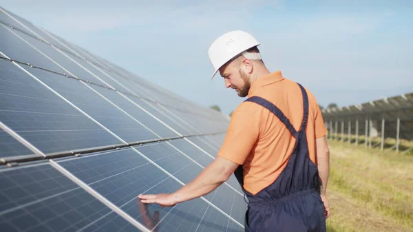 Locuri de muncă durabile de energie verde, tehnician panou solar care lucrează cu panouri solare. Asistența lucrătorului tehnic în uniformă verifică funcționarea și eficiența panourilor solare fotovoltaice Fotografie de stoc