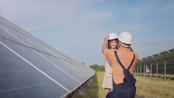 Um jovem pai é engenheiro explica a sua filha uma operação e desempenho de painéis solares fotovoltaicos ao pôr do sol. Conceito: energia renovável, tecnologia, eletricidade, verde, futuro, família — Fotografia de Stock