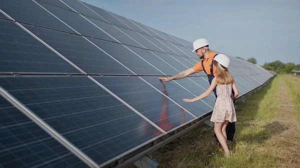 En far som jobber i et solkraftverk forteller datteren om arbeidet sitt, viser grønn energi, solcellepaneler. Skyting på et solkraftverk. Bevaring av planeten vår, global oppvarming – stockfoto