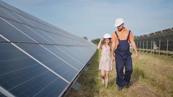 พ่อทํางานในโรงไฟฟ้าพลังงานแสงอาทิตย์ บอกลูกสาวของเขาเกี่ยวกับงานของเขา แสดงพลังงานสีเขียว แผงโซลาร์เซลล์ ยิงที่โรงไฟฟ้าพลังงานแสงอาทิตย์ เด็กศึกษาพลังงานแสงอาทิตย์ — ภาพถ่ายสต็อก