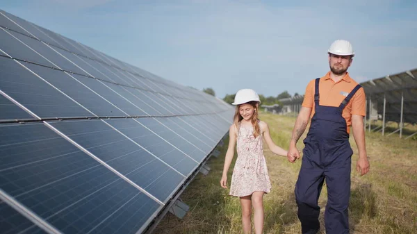 En far som jobber i et solkraftverk forteller datteren om arbeidet sitt, viser grønn energi, solcellepaneler. Skyting på et solkraftverk. Barnet studerer solenergi – stockfoto